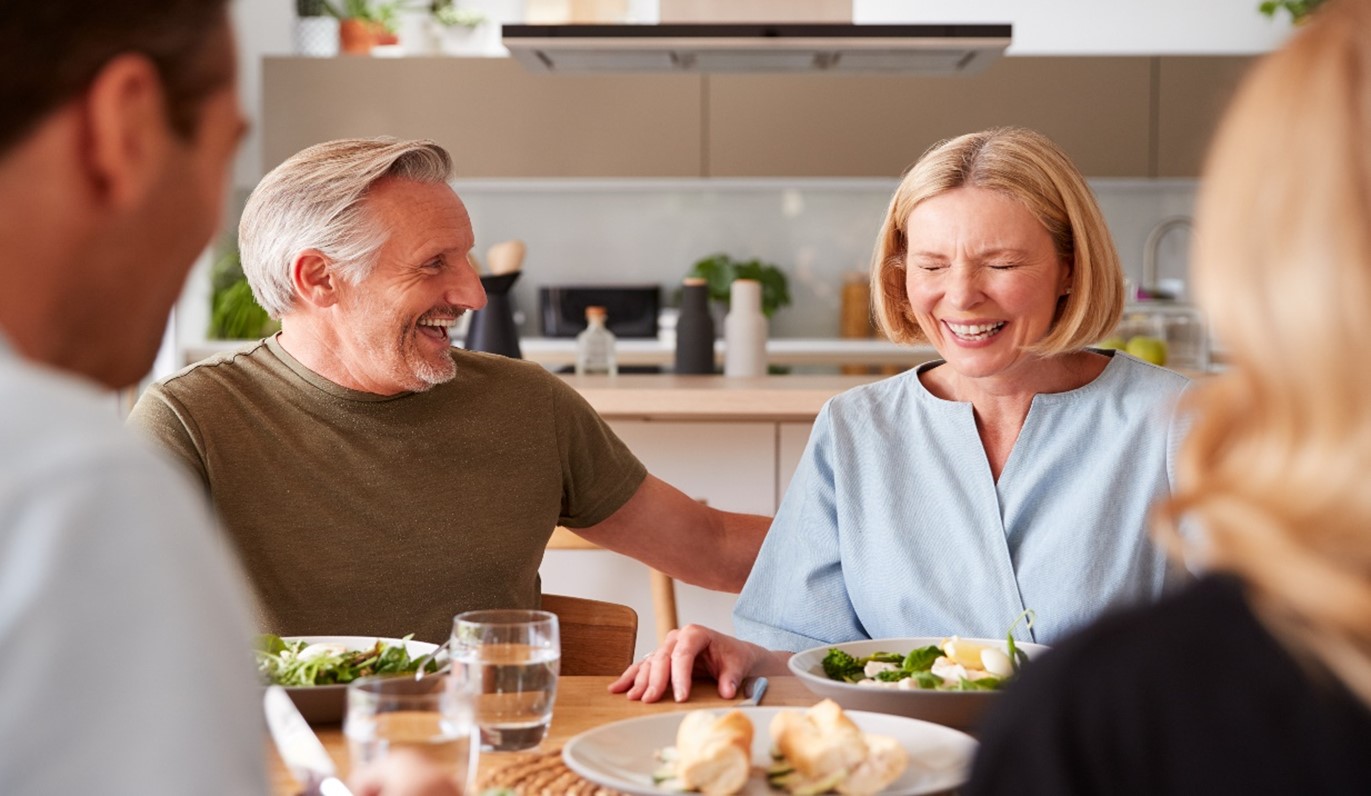 Image of family laughing together at table.